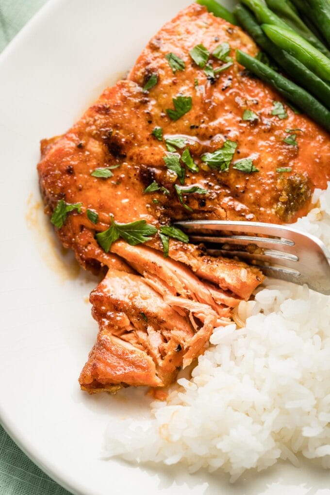 Close-up of a perfectly cooked salmon filet being flaked with a fork.