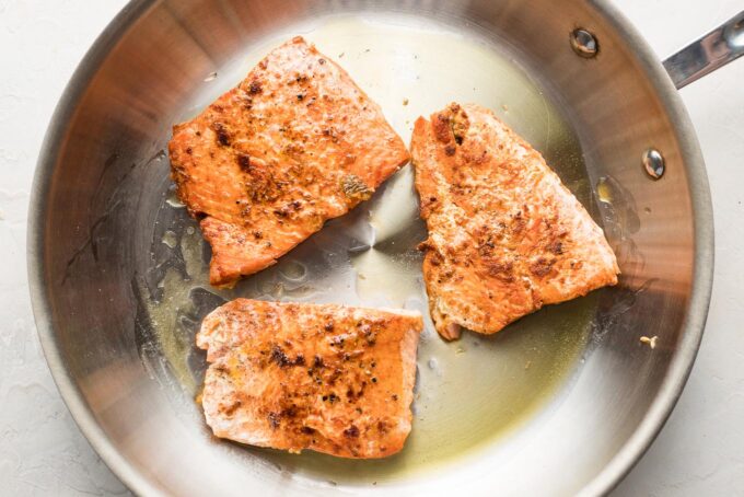 Cooked salmon filets in a pan.