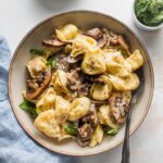 Small pasta bowl filled with cheese tortellini cooked with mushrooms, butter, and Parmesan.