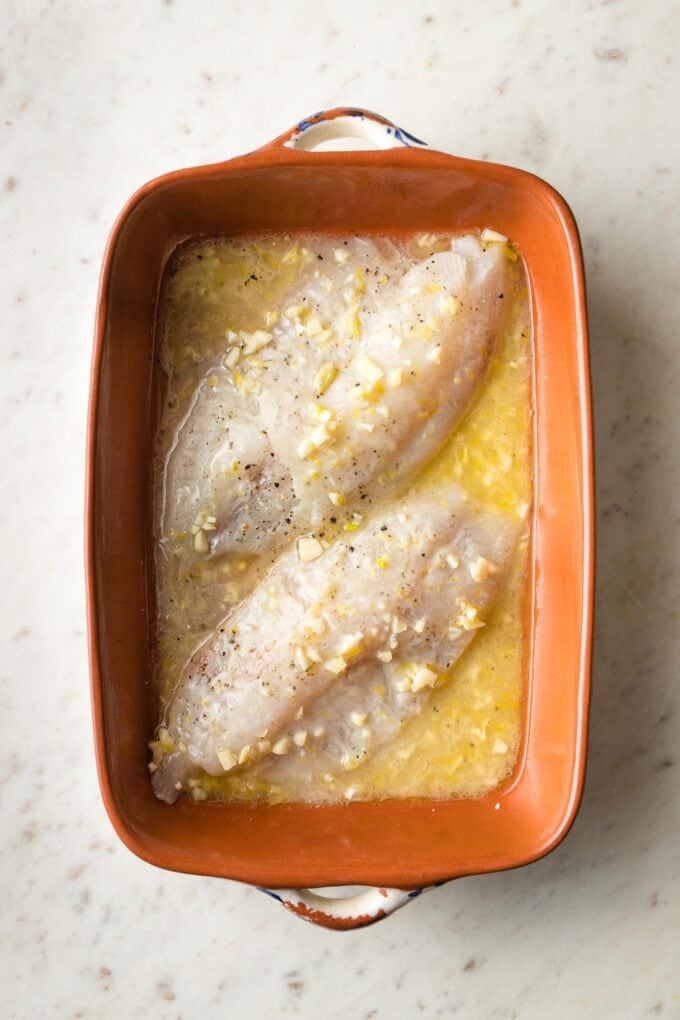 Butter poured over fish in pan.