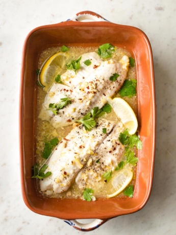 Baked tilapia with lemon in an earthenware pan.