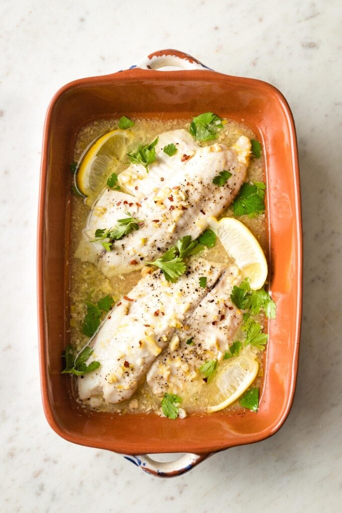 Baked tilapia with lemon in an earthenware pan.