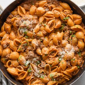 Large skillet full of a 20 minute dish of chili garlic beef and shells with a light tomato cream sauce.