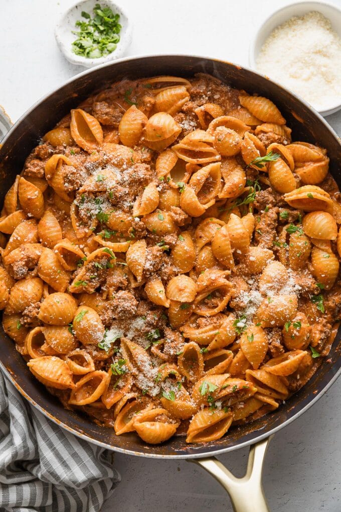 Large skillet full of a 20 minute dish of chili garlic beef and shells with a light tomato cream sauce.