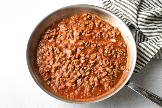 Seasoned beef in skillet with tomato sauce.