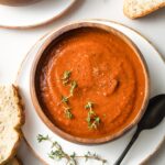 Bowls of tomato soup with slices of bread.