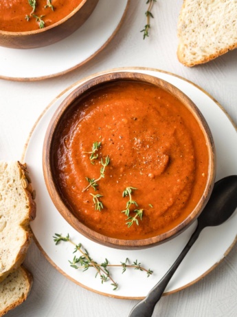 Bowls of tomato soup with slices of bread.