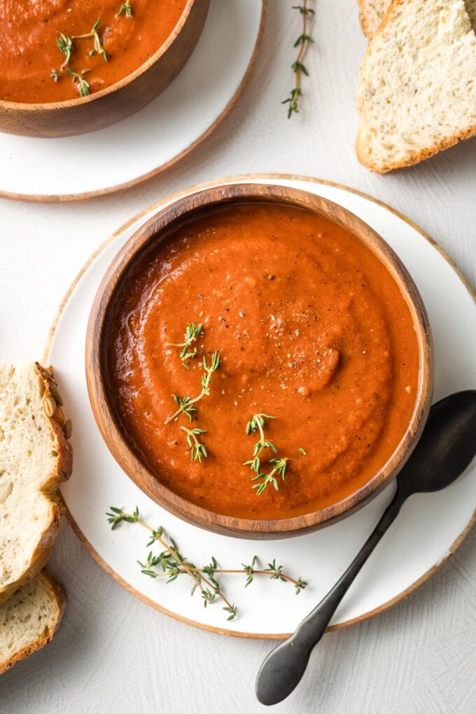 Bowls of tomato soup with slices of bread.