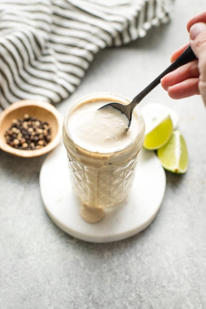 Small glass jar holding lime Caesar dressing.