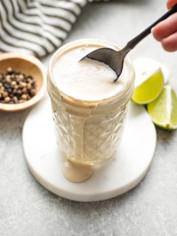 Small glass jar holding lime Caesar dressing.