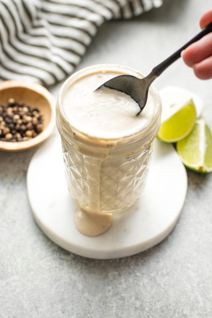 Small glass jar holding lime Caesar dressing.