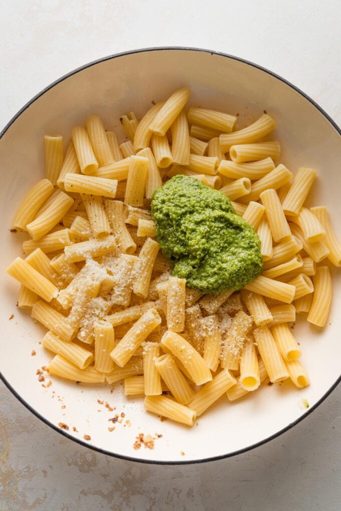 Drained pasta mixed with pesto and Parmesan in a large skillet.