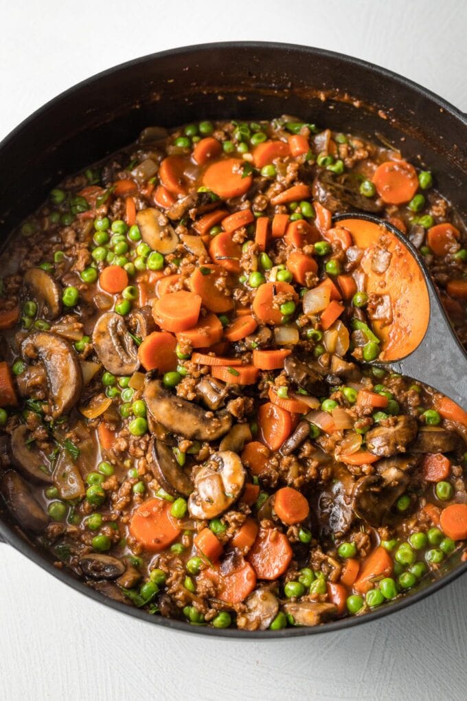 Peas added to gravy and veggies in skillet.