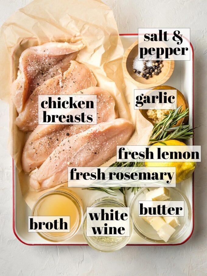 Labeled photo showing raw chicken breasts, kosher salt, black pepper, garlic, fresh lemon, fresh rosemary, butter, white wine, and broth.
