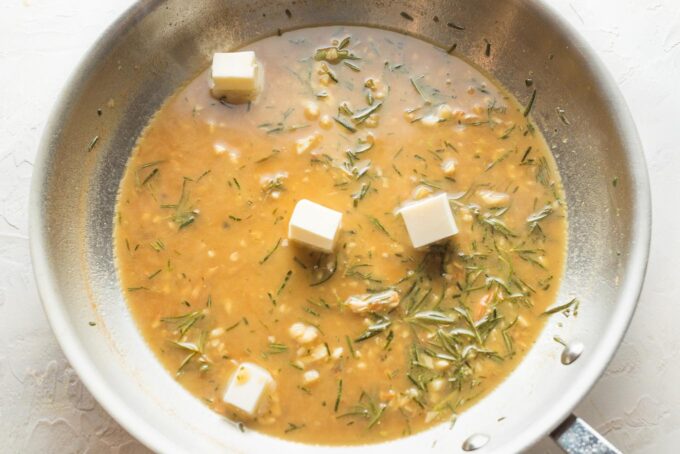 Step 4: melting pats of butter into a lemon rosemary pan sauce to be served with chicken.