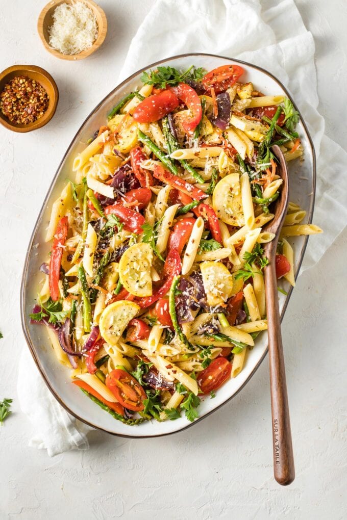 Large plate filled with a lemon herb pasta primavera and a wooden serving spoon.