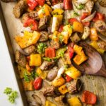 Large sheet pan filled with roasted chicken sausage, peppers, and shallots.