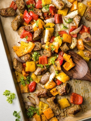 Large sheet pan filled with roasted chicken sausage, peppers, and shallots.