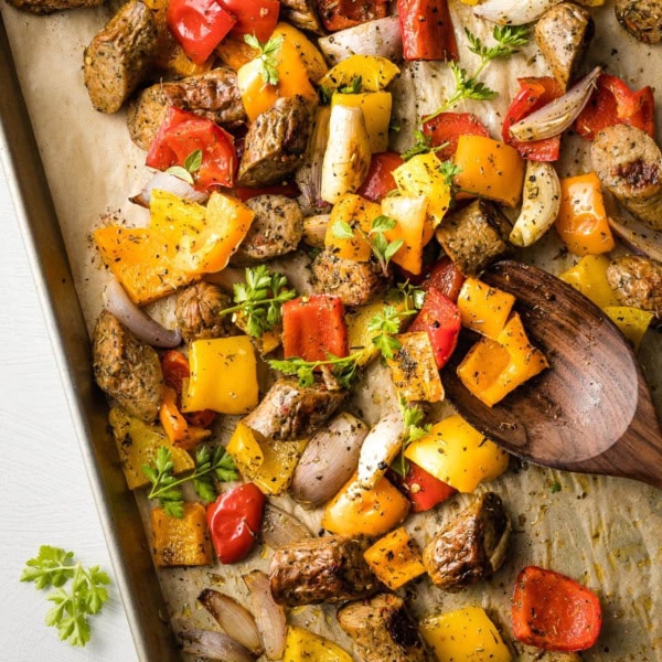 Large sheet pan filled with roasted chicken sausage, peppers, and shallots.
