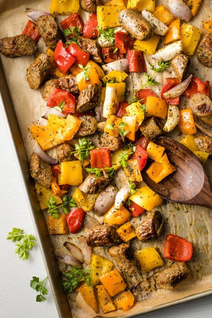 Large sheet pan filled with roasted chicken sausage, peppers, and shallots.