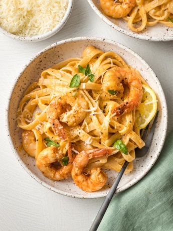 Bowls of blackened shrimp Alfredo, garnished with parsley and ready to eat.