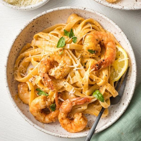 Bowls of blackened shrimp Alfredo, garnished with parsley and ready to eat.