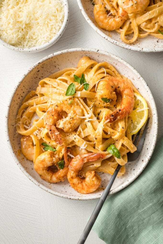 Bowls of blackened shrimp Alfredo, garnished with parsley and ready to eat.