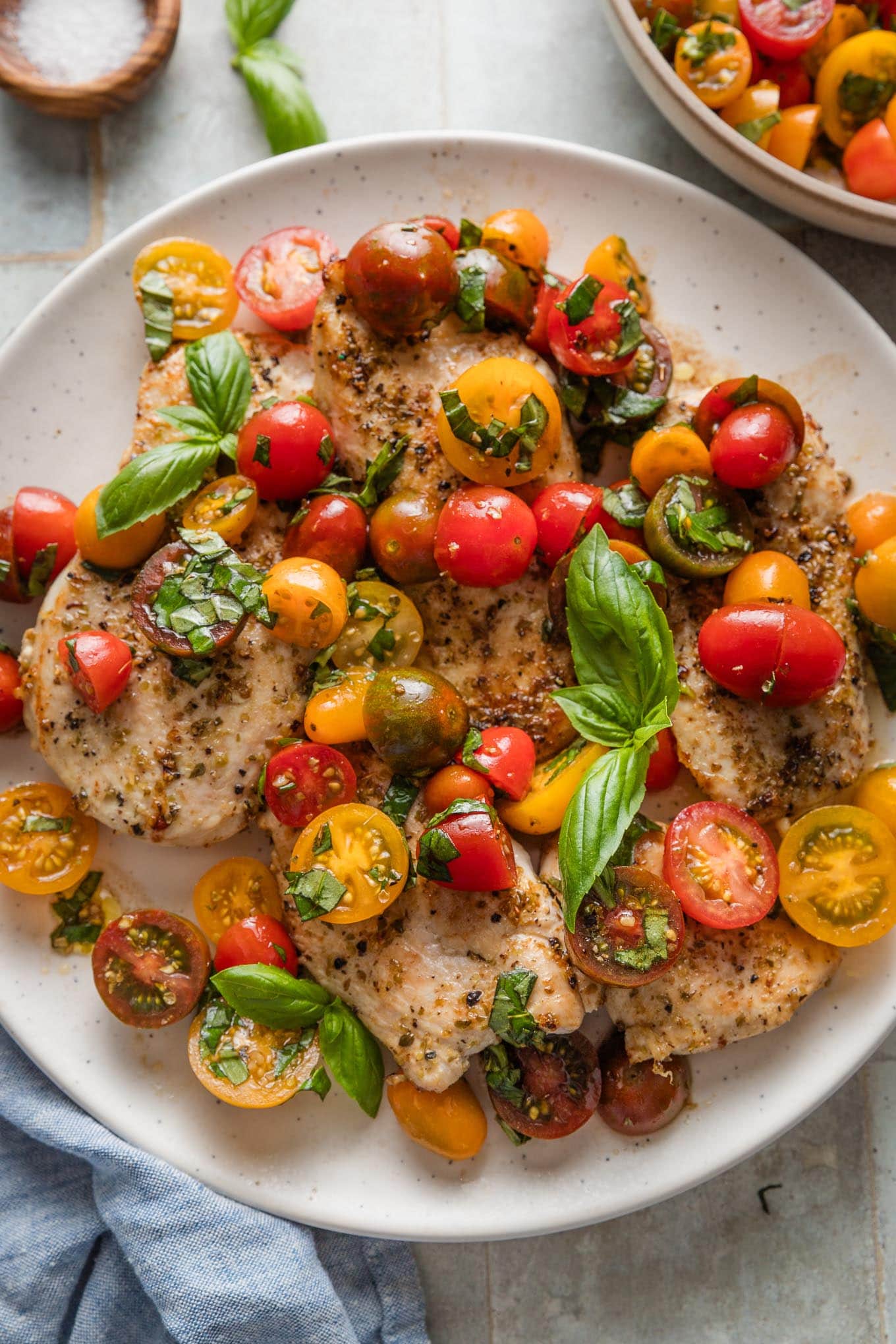 Platter filled with chicken breasts topped with tomato basil bruschetta.