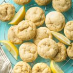 Wire rack piled high with soft lemon sugar cookies on a blue background.