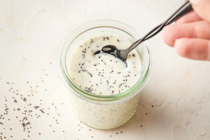 A small spoon scooping out a bit of honey poppy seed dressing.