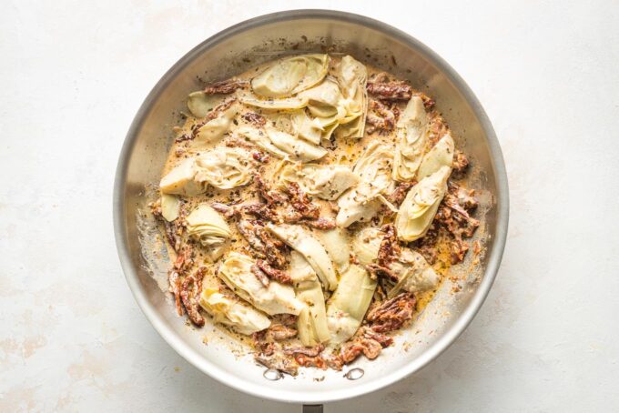 Artichokes and seasoning added to skillet.