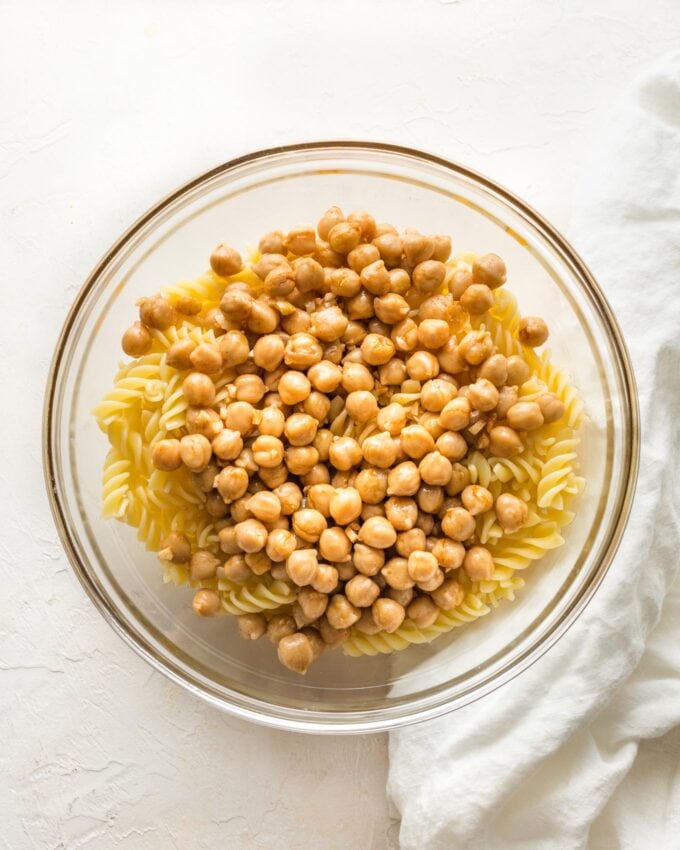 Hot pasta in a prep bowl with chickpeas poured on top.
