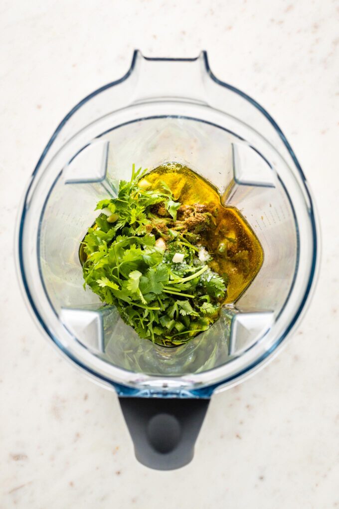 Ingredients for dressing combined in the bowl of a Vitamix.