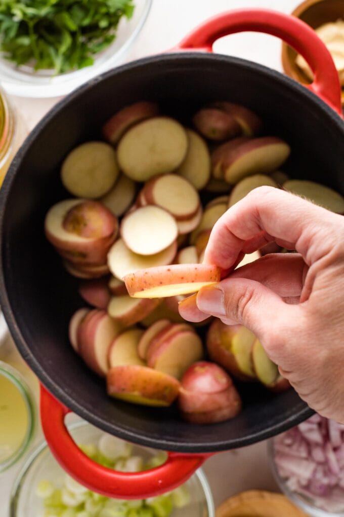 Close-up of a hand holding a sliced potato to show it's about 1/4