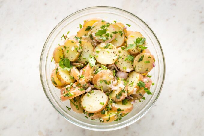 Finished potato salad tossed together in a clear prep bowl.