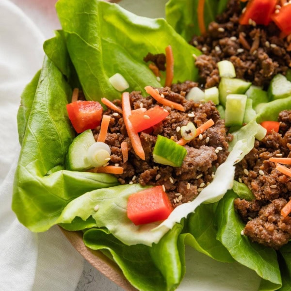 Angled view of Korean beef lettuce wraps arranged on a plate.