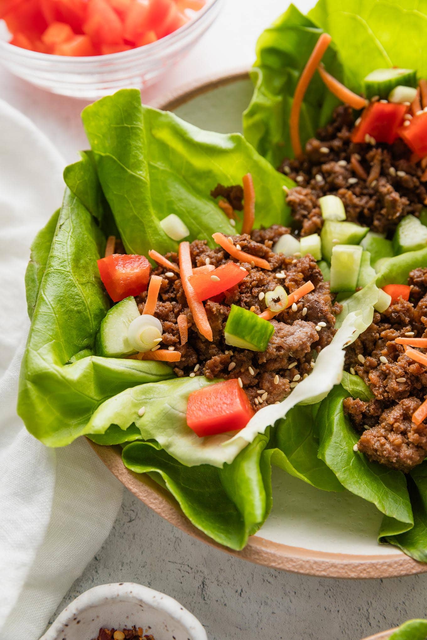 Angled view of Korean beef lettuce wraps arranged on a plate.