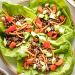 Three Korean beef lettuce wraps piled into a white bowl, ready to eat.