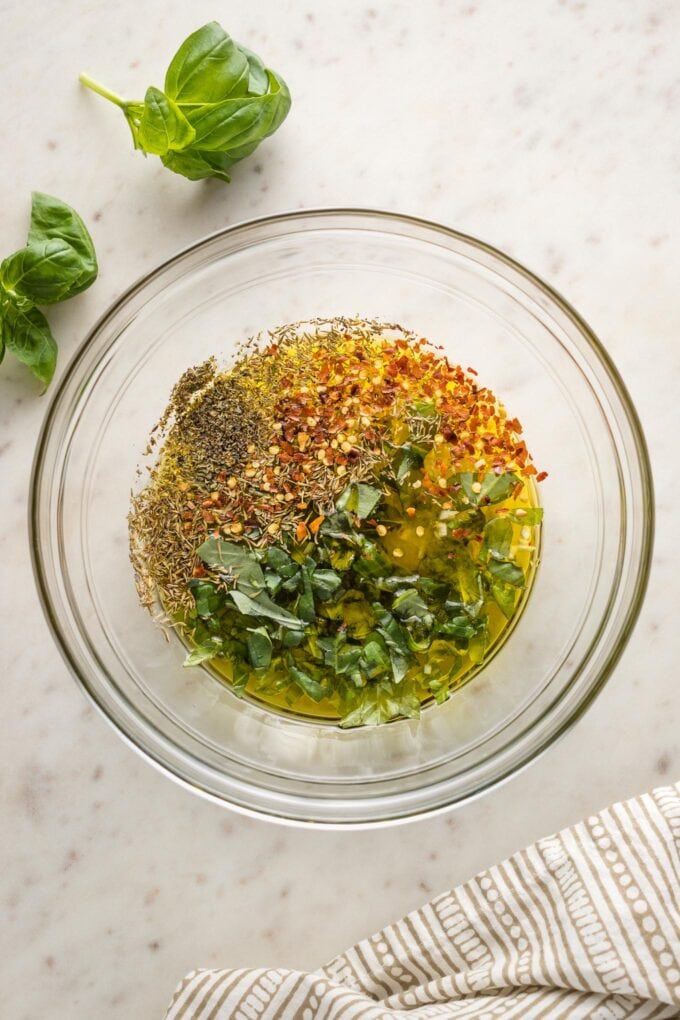 Pyrex bowl with olive oil, garlic, red pepper, and herbs.