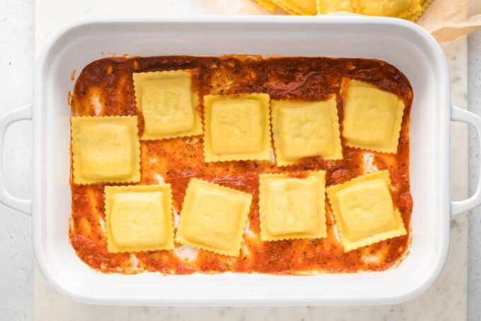 Nine ravioli spread out on top of marinara.