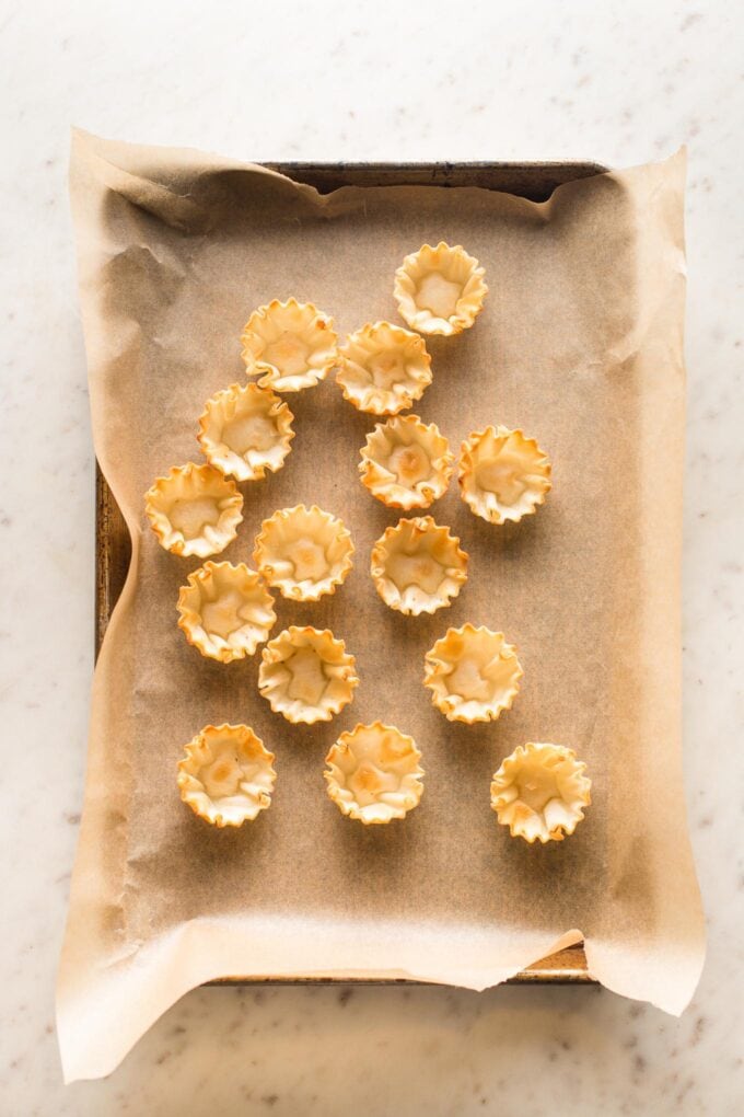 Miniature phyllo cups arranged on a parchment-lined baking sheet.