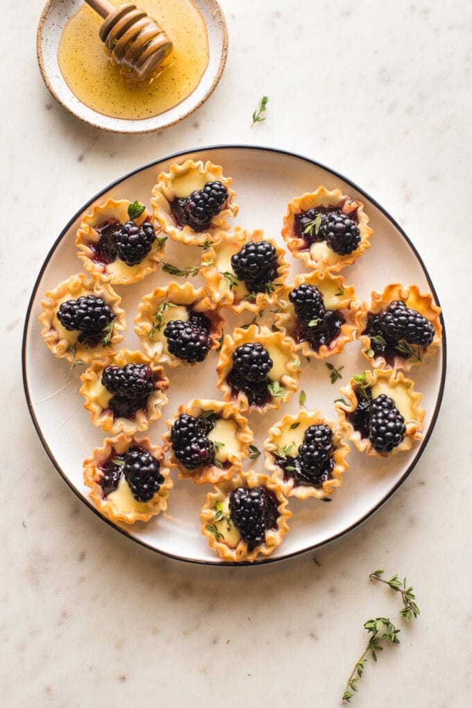 Small white plate filled with blackberry brie bites in mini phyllo cups.