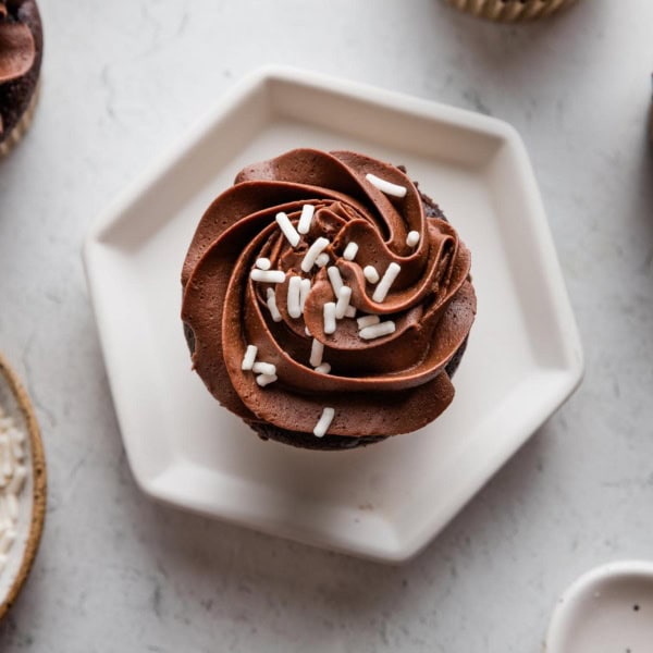 Close up of a chocolate buttermilk cupcake with a rosette piped of chocolate frosting on top.