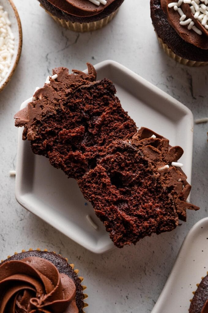 Interior view of a chocolate buttermilk cupcake, showing a moist, tender crumb interior and simple chocolate frosting on top.