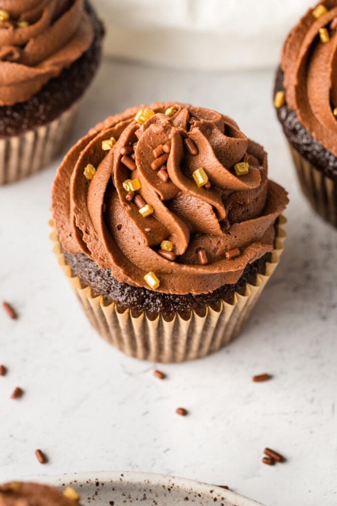 Close up of a chocolate buttermilk cupcake with gold sprinkles.