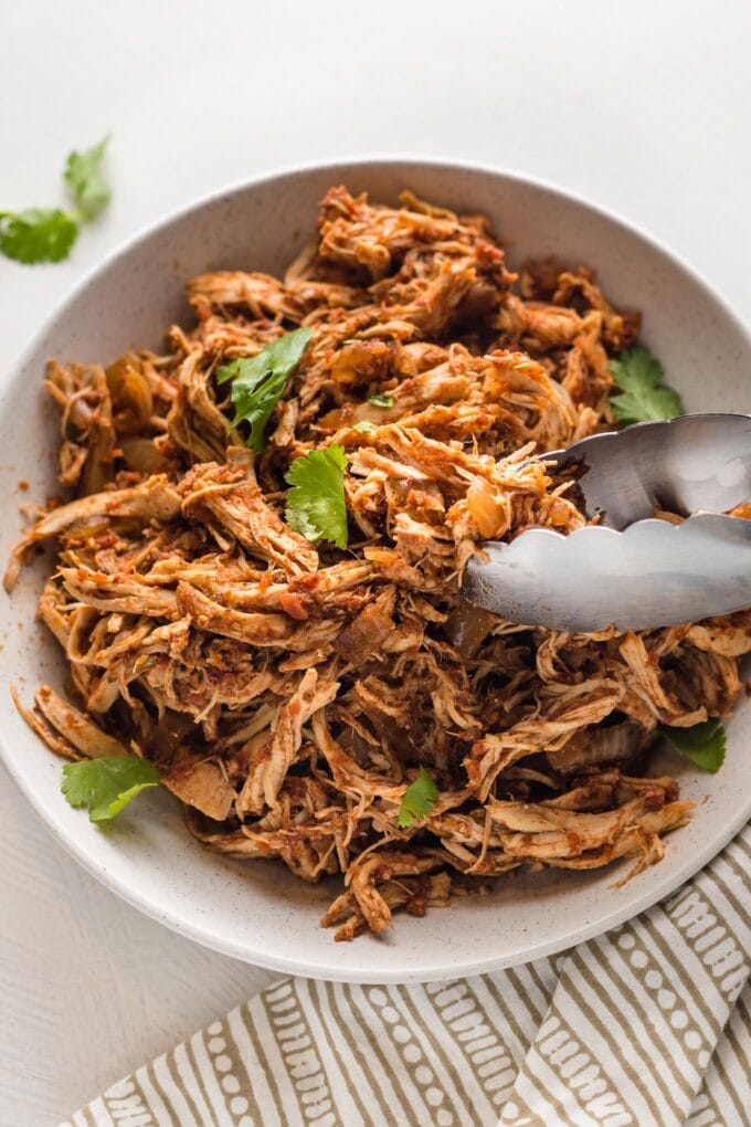 Close up of Mexican shredded chicken transferred from a slow cooker to a serving bowl.