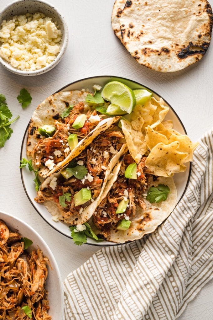 Small plate holding three shredded chicken tacos.