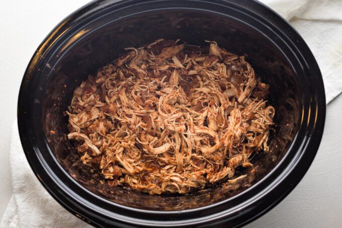 Shredded Mexican chicken in the bowl of a slow cooker.