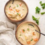 Two bowls of creamy turkey and dumplings soup.