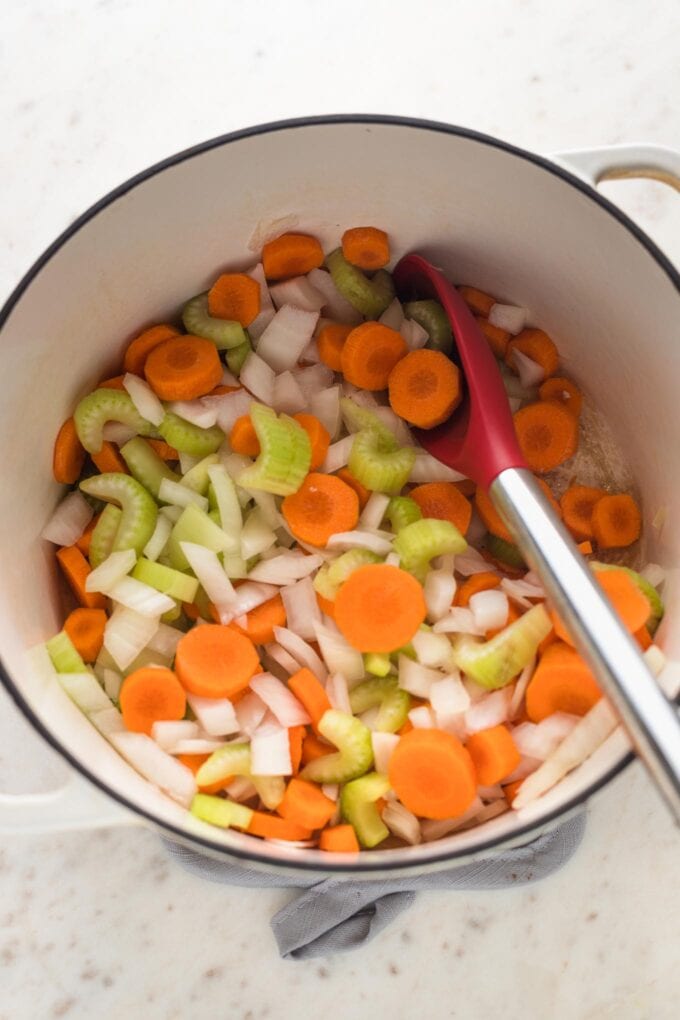 Carrots, onions, and celery cooking in a Dutch oven.